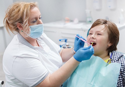 A boy getting fluoride treatment from a dentist