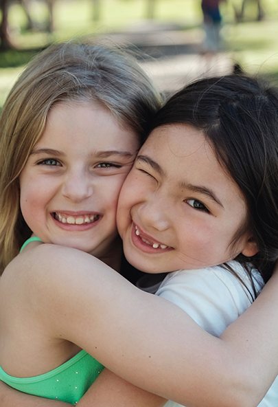 Two young girls smiling and hugging after visiting their pediatric dental office in Bakersfield