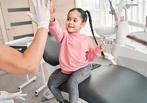 Young girl giving a high five to her dentist
