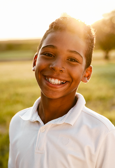 Boy grinning outdoors after seeing his emergency dentist for children in Bakersfield