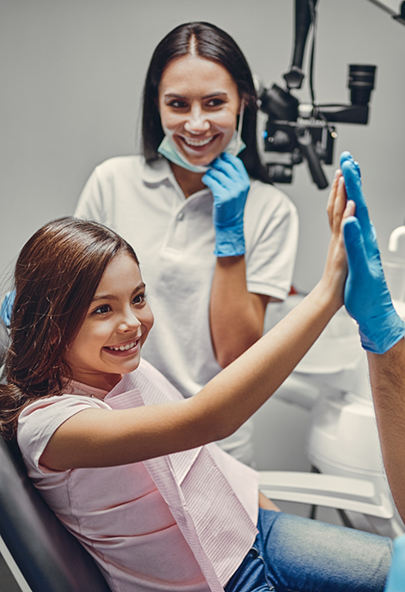 Girl in the dental chair giving a high five to her children's dentist in Bakersfield