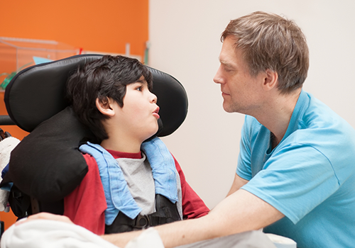 Pediatric dentist talking with a boy in a wheelchair