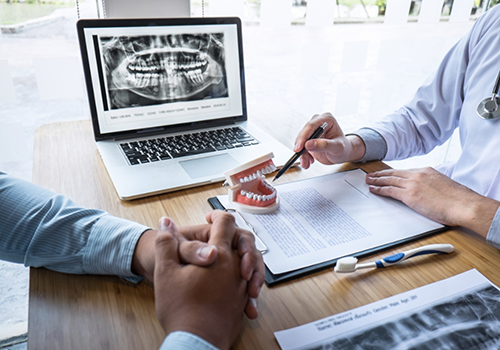 Person sitting across a table from a dentist during a consultation