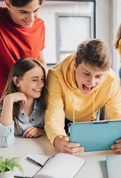 Three laughing teenagers looking at a tablet screen