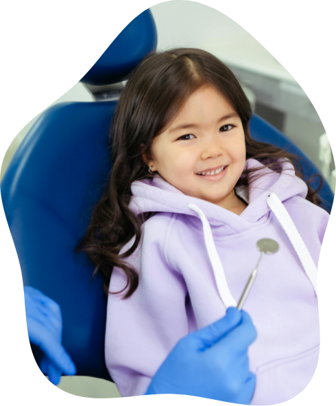 Young girl in a light purple hoodie smiling in the dental chair