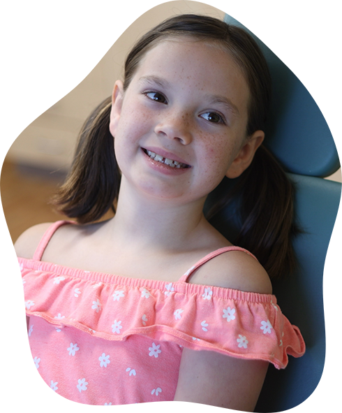 Young girl in a light purple hoodie smiling in the dental chair