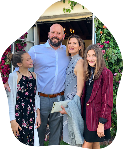Doctor Purdy standing with his wife and two daughters in front of a restaurant