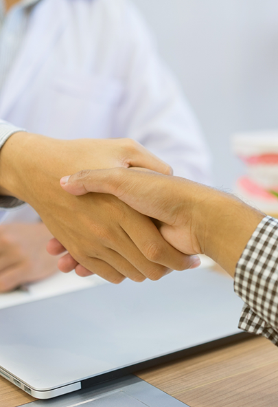 Dentist shaking hands with a patient across a table