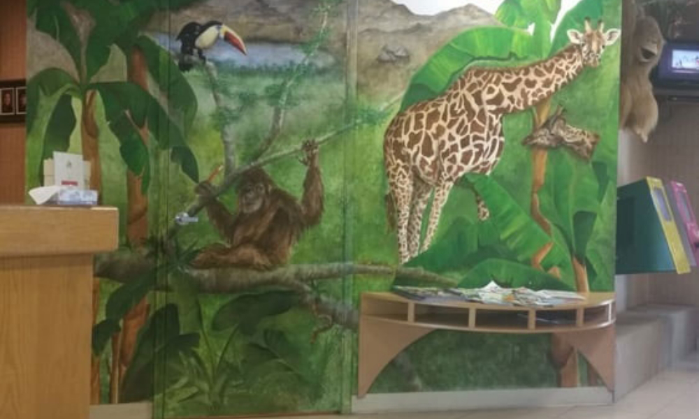Close up of wall mural showing an ape and a giraffe in the trees