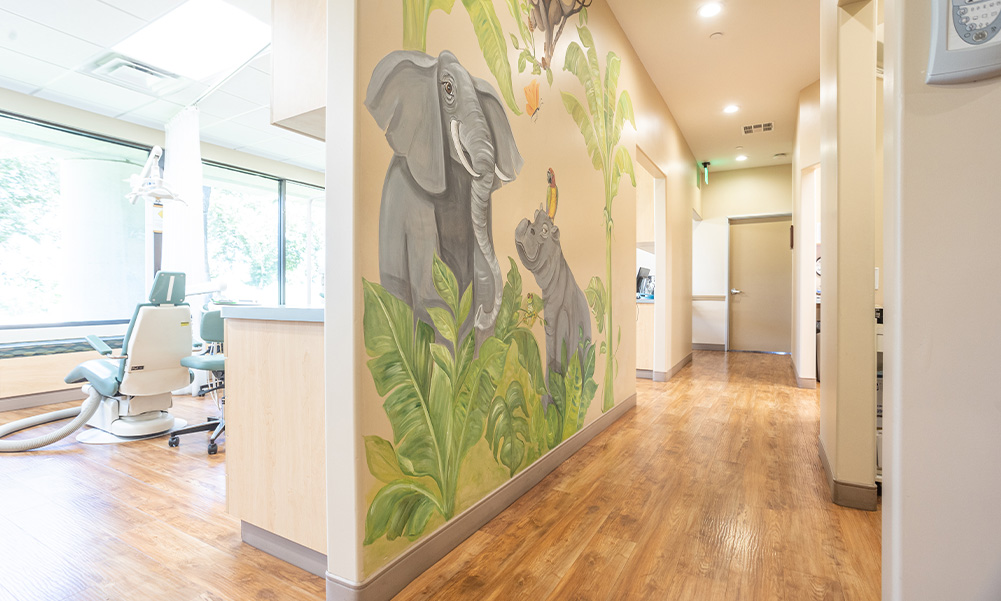 Wall art of an elephant and a hippo with a bird perched on its head