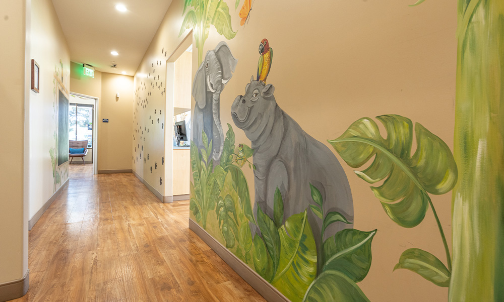 Wall art of an elephant and a hippo with a bird perched on its head