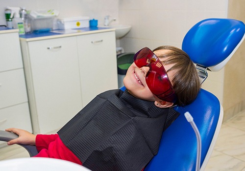 Kid with glasses smiling from patient’s chair