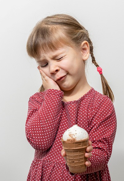 Little girl holding ice cream and experiencing dental emergency in Bakersfield