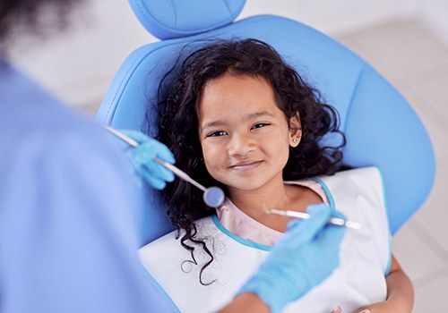 Little girl with curly hair in dental chair about to have exam