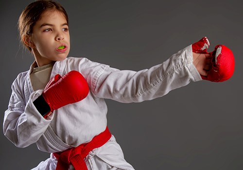 Girl in martial arts uniform with mouthguard over teeth