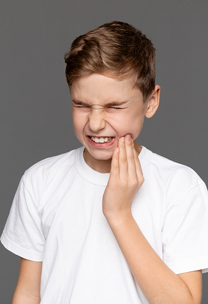 Boy wincing and holding the side of his face in pain