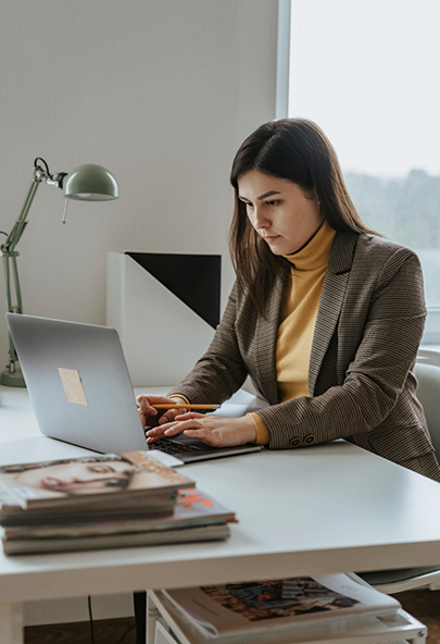 Office worker sitting at her desk and typing on a laptop