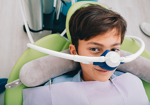 Boy in the dental chair wearing a nitrous oxide mask over his nose