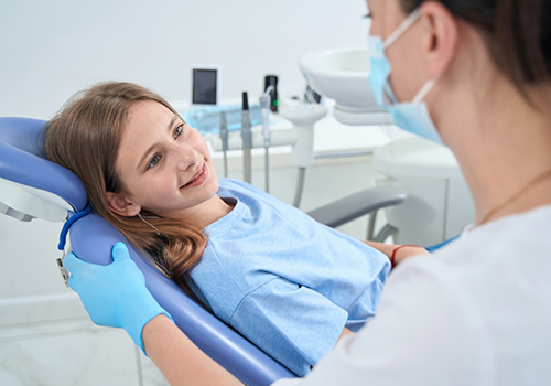 Girl in the dental chair listening to her dentist