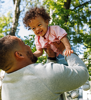 Father holding his toddler above his head outdoors