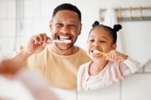 Dad and daughter brushing their teeth together