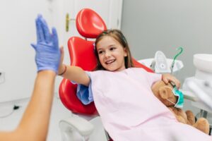 Child high-fiving their dentist after a tooth extraction