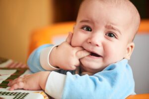 Teething baby with finger in their mouth.